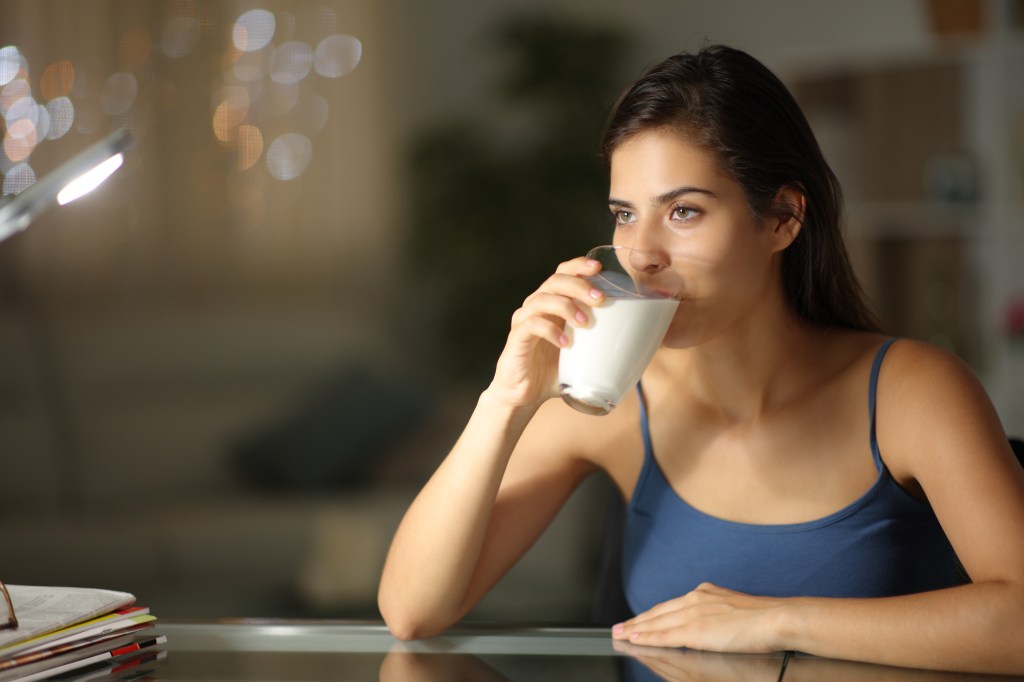 The woman drinks a glass of milk.